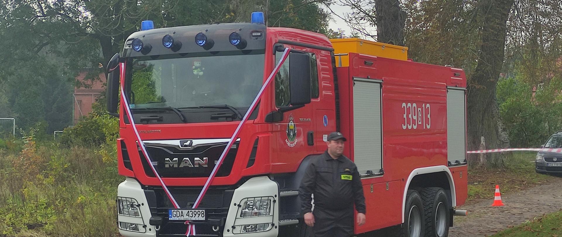 Samochód gaśniczy oraz obok stoi druh.