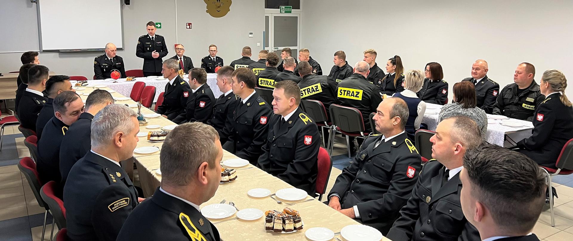 Wigilia 2022 w KP PSP w Wąbrzeźnie. Na zdjęciu przemawiający Komendant Powiatowy PSP w Wąbrzeźnie, zaproszeni goście oraz funkcjonariusze. 