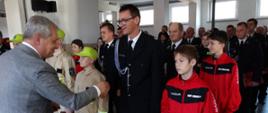 Strażacy z OSP w mundurach wyjściowych i MDP w ubraniach koszarowych koloru beżowego oraz czerwonych dresach otrzymują promesy