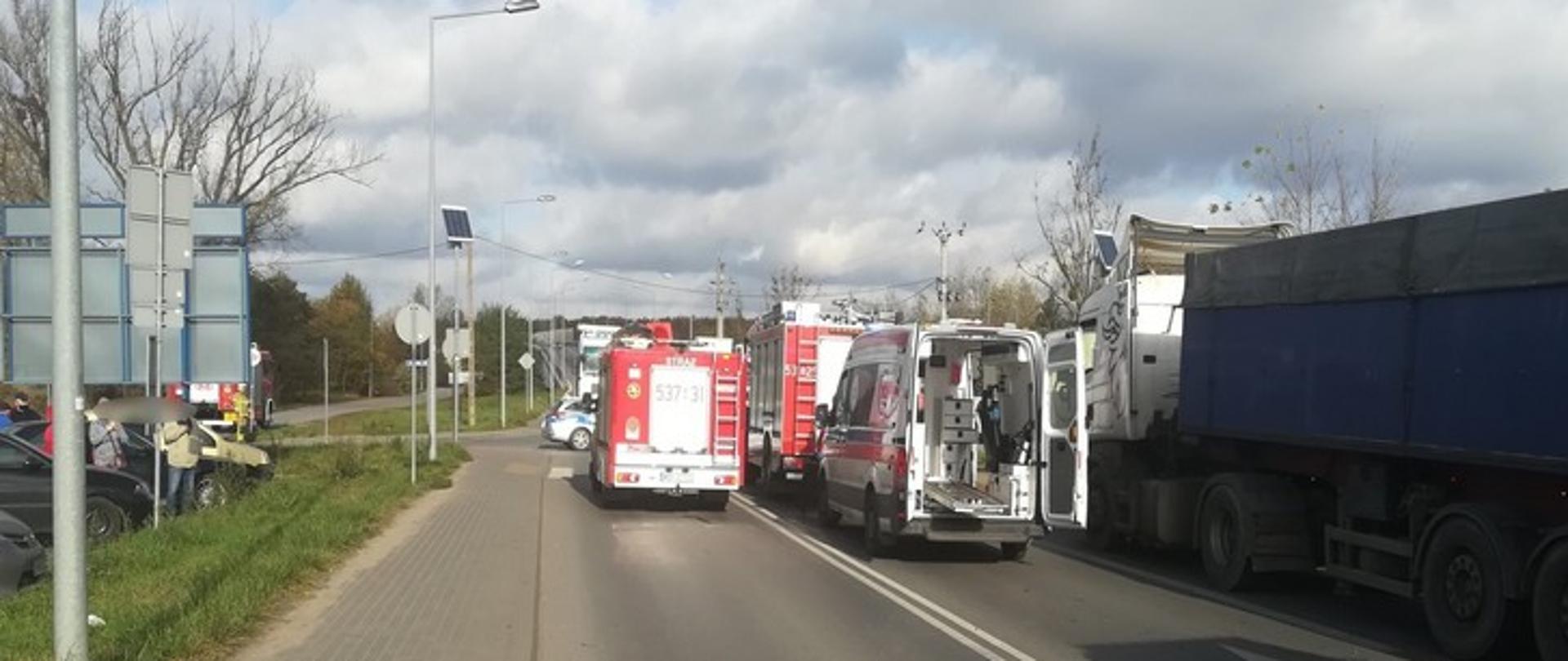 Zdjęcie przedstawia ulicę Leśną w Nowym Dworze Mazowieckim, na której znajdują się: pojazdy straży pożarnej, karetka pogotowia ratunkowego oraz samochód ciężarowy, który uległ wypadkowi.