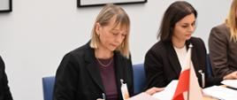 Przy stole konferencyjnym siedzą dwie kobiety i czytają dokumenty