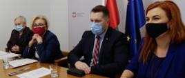 Sekretarz Stanu w MEN Marzena Machałek, Minister Edukacji i Nauki Przemysław Czarnek i Rzecznik Prasowy MEN Anna Ostrowska siedzą przy stole. W tle flaga Polski i Unii Europejskiej.