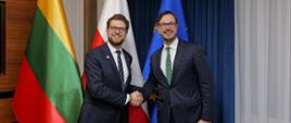 Minister Jakub Jaworowski oraz minister gospodarki i innowacji Litwy, Lukas Savickas stoją na tle flag.
