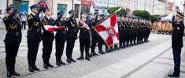 Rynek, strażacy w umundurowaniu galowym stoją w szeregu, sztandar, przed generałem
