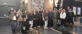 Grupa młodzieży w przystrojonym świątecznie kinie