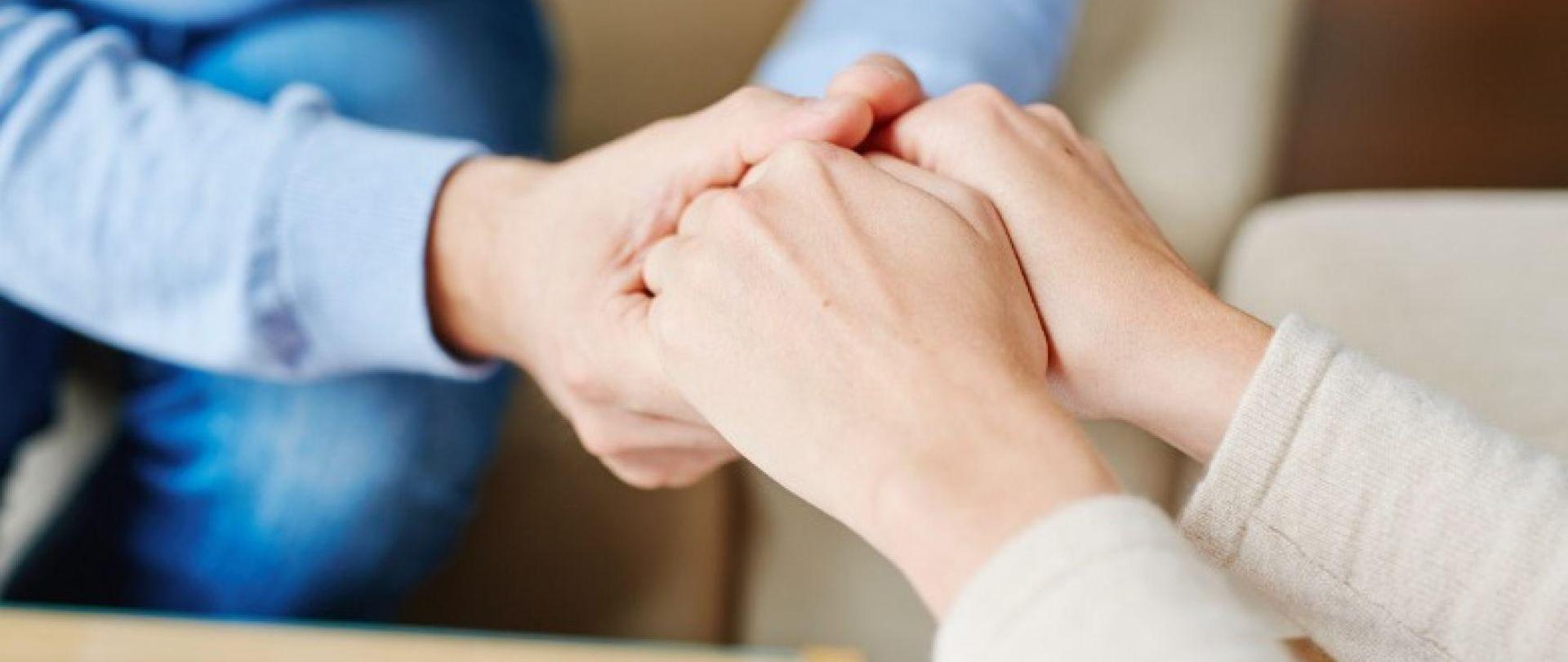 dwie osoby siedzą i ściskają dłonie