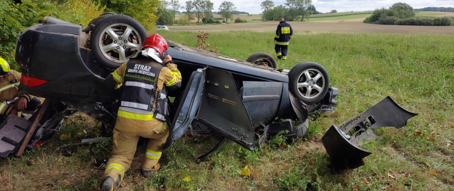 Zdjęcie przedstawia uszkodzony pojazd oraz ratowników PSP podczas przeszukiwań wraku