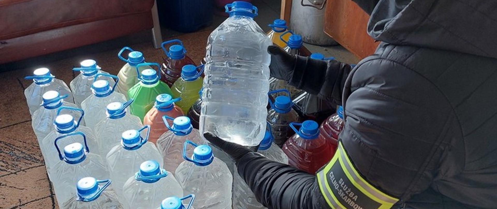 Funkcjonariusz trzyma butlę z alkoholem