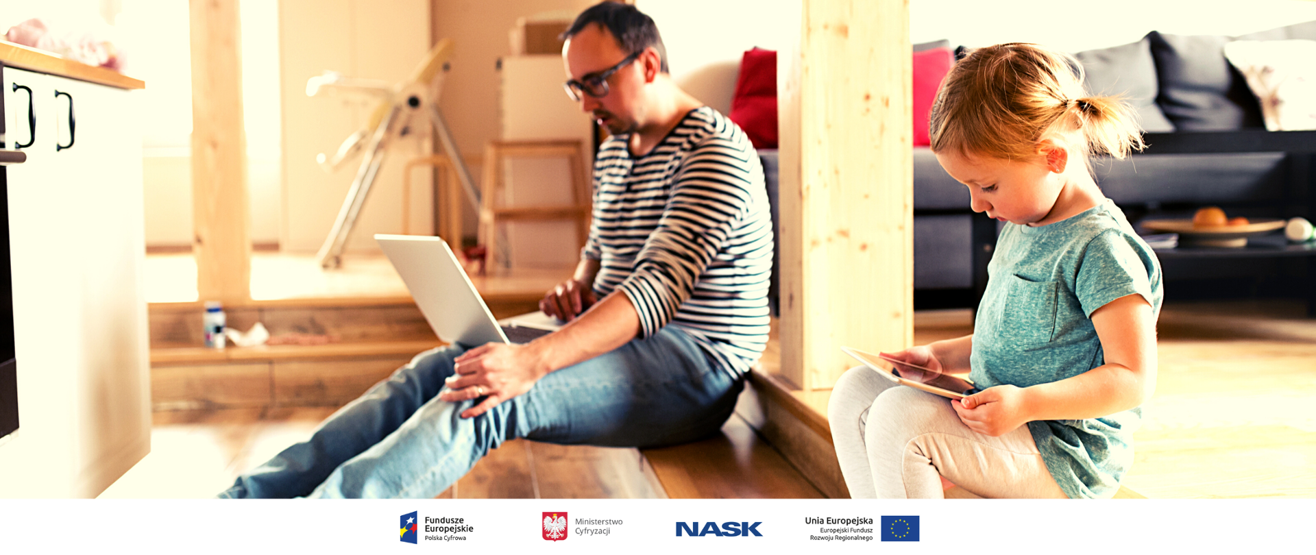 Tata z córeczką siedzą w domu na schodach. Tata pracuje na komputerze a córeczka bawi się na tablecie. 