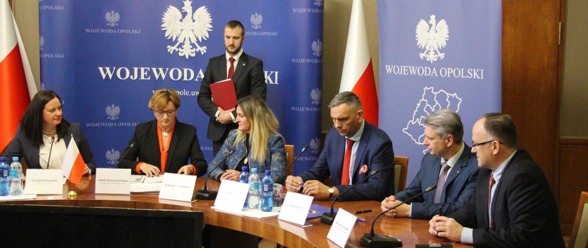 Podpisanie umów na unijne dofinansowanie w Opolskim Urzędzie Wojewódzkim. Przy stole siedzi sześć osób, wśród nich wiceminister zdrowia Józefa Szczurek-Żelazko oraz wicewojewoda Violetta Porowska.