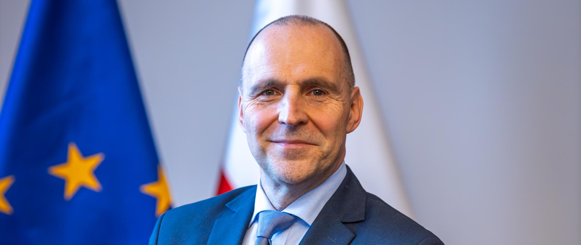 wojewoda Adam Rudawski stoi na tle flag: polskiej i unijnej