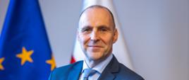 wojewoda Adam Rudawski stoi na tle flag: polskiej i unijnej
