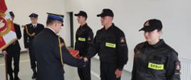 Zdjęcie przedstawia Komendanta Powiatowego PSP w Lwówku Śląskim w trakcie wręczania aktu mianowania nowo przyjętym strażakom. 