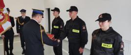 Zdjęcie przedstawia Komendanta Powiatowego PSP w Lwówku Śląskim w trakcie wręczania aktu mianowania nowo przyjętym strażakom. 