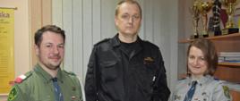 Harcerze i zastępca komendanta powiatowego PSP prezentują odznakę