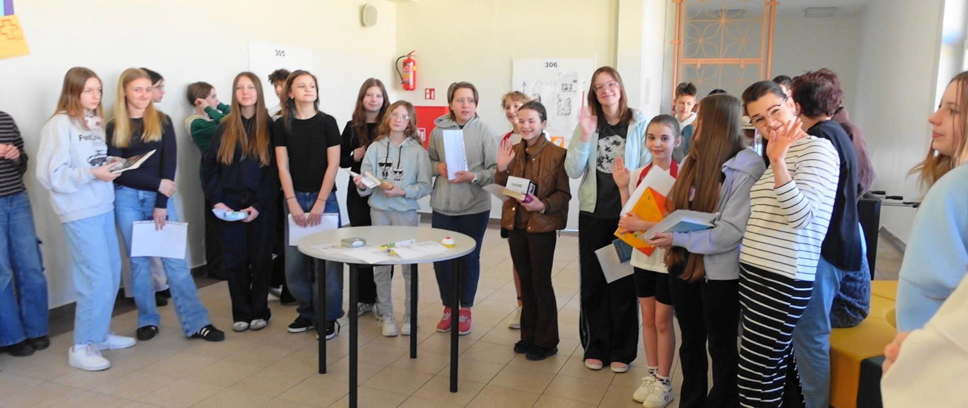 Uczniowie nagradzani książkami i dyplomami na korytarzu szkoły