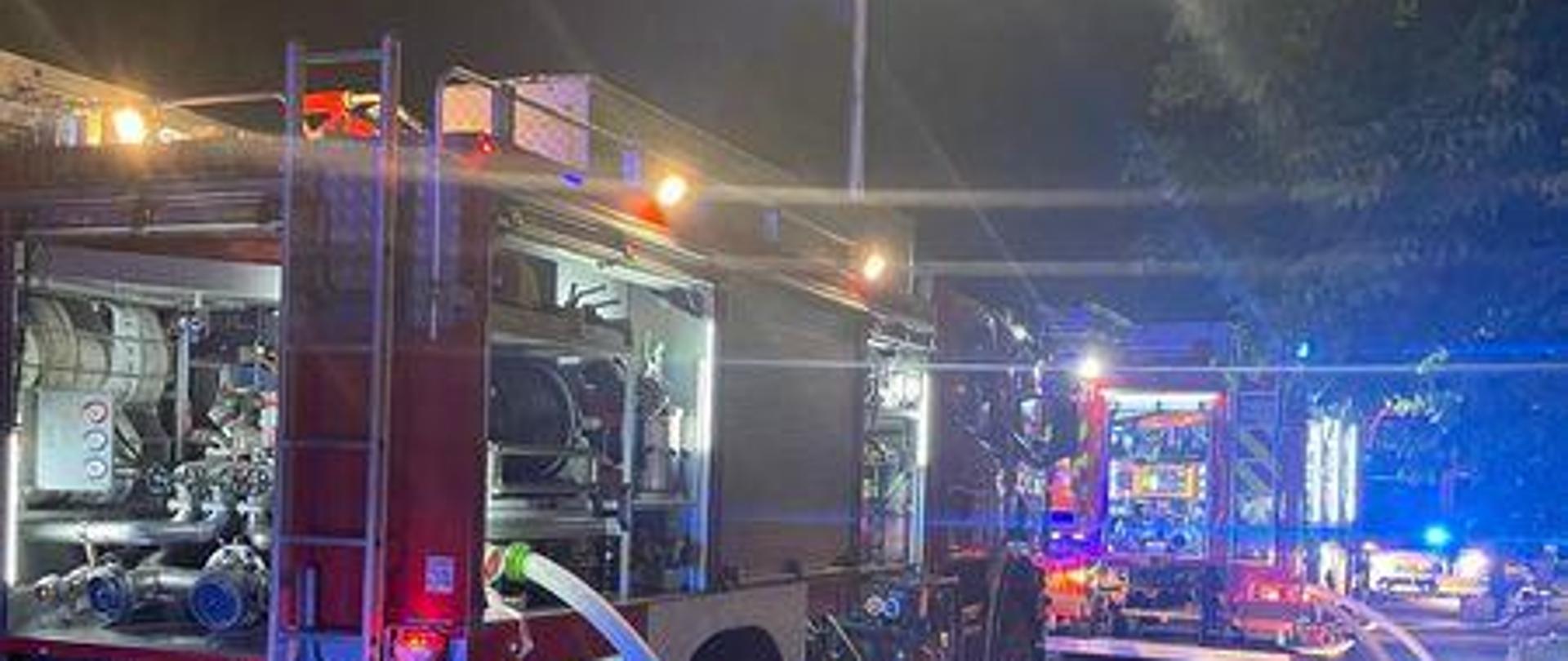 Zdjęcie przedstawia pojazdy pożarnicze podczas pożaru poddasza wielorodzinnego budynku mieszkalnego.