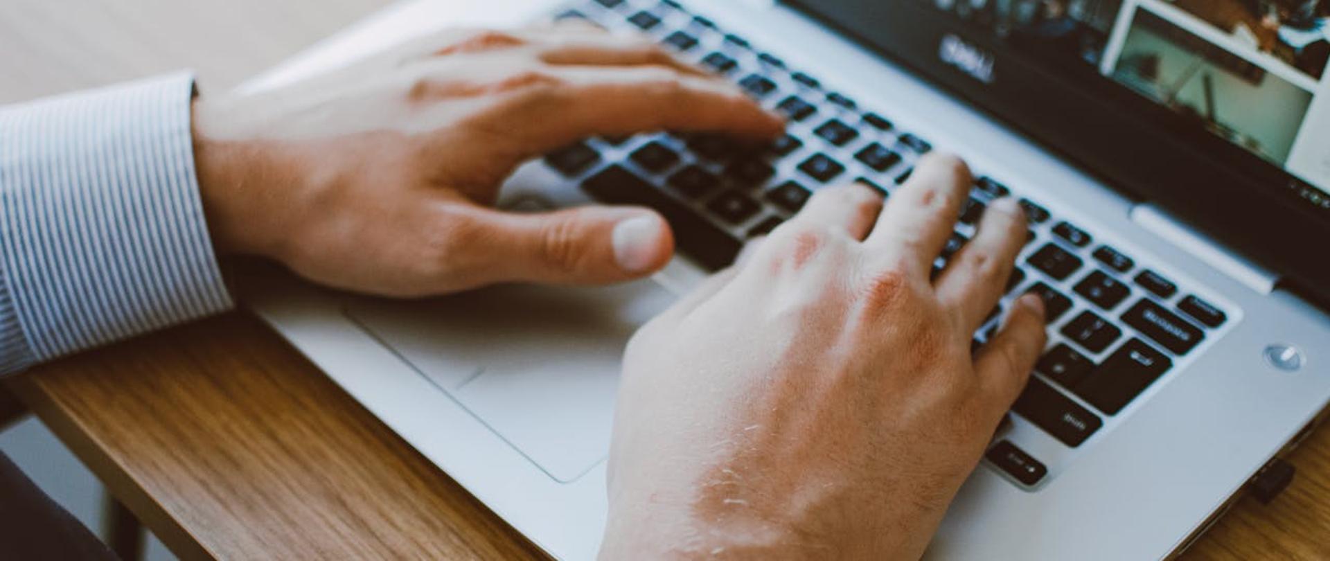 ręce piszące na klawiaturze laptopa
