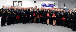 Uczestnicy uroczystości wręczenia promes i decyzji o przyznaniu świadczenia ratowniczego stoją w sali im. J. Tuliszkowskiego w KW PSP Gdańsk