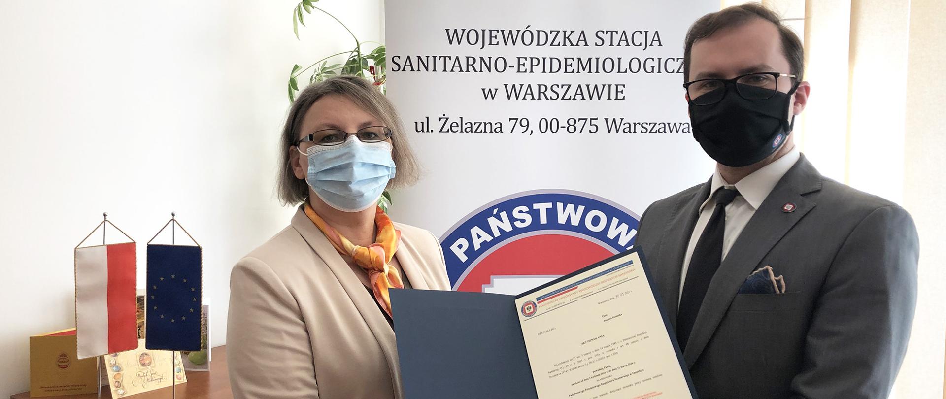 Od lewej stoi nowo powołana PPIS w Ostrołęce, pani mgr inż. Joanna Stomska, obok po prawej MPWIS - dr n. med.Przemysław Rzodkiewicz wręczający dokument z powołaniem 