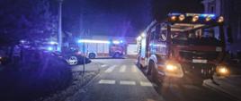 Samochody strażackie stoją na drodze przed kościołem. Zdjęcie wykonane w porze nocnej.