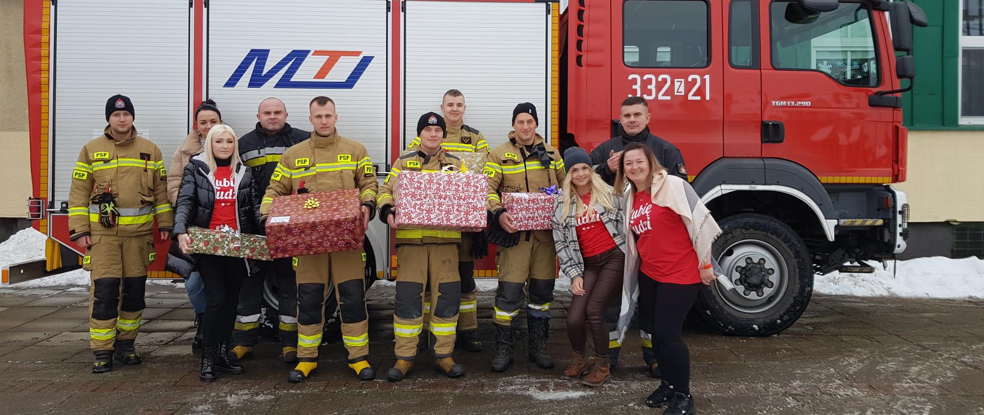 Przekazania szlachetnej paczki przez JRG2 (na tle pojazdu ratowniczo-gaśniczego JRG2)