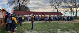 Zdjęcie przedstawia dzieci i młodzież szkolną zgromadzoną na terenie zielony, pod wiatami. W tle widoczne tereny zielone