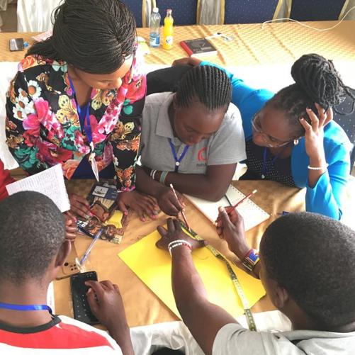 Przy stole siedzi grupa nauczycielek i nauczycieli i korzysta z pomocy dydaktycznych