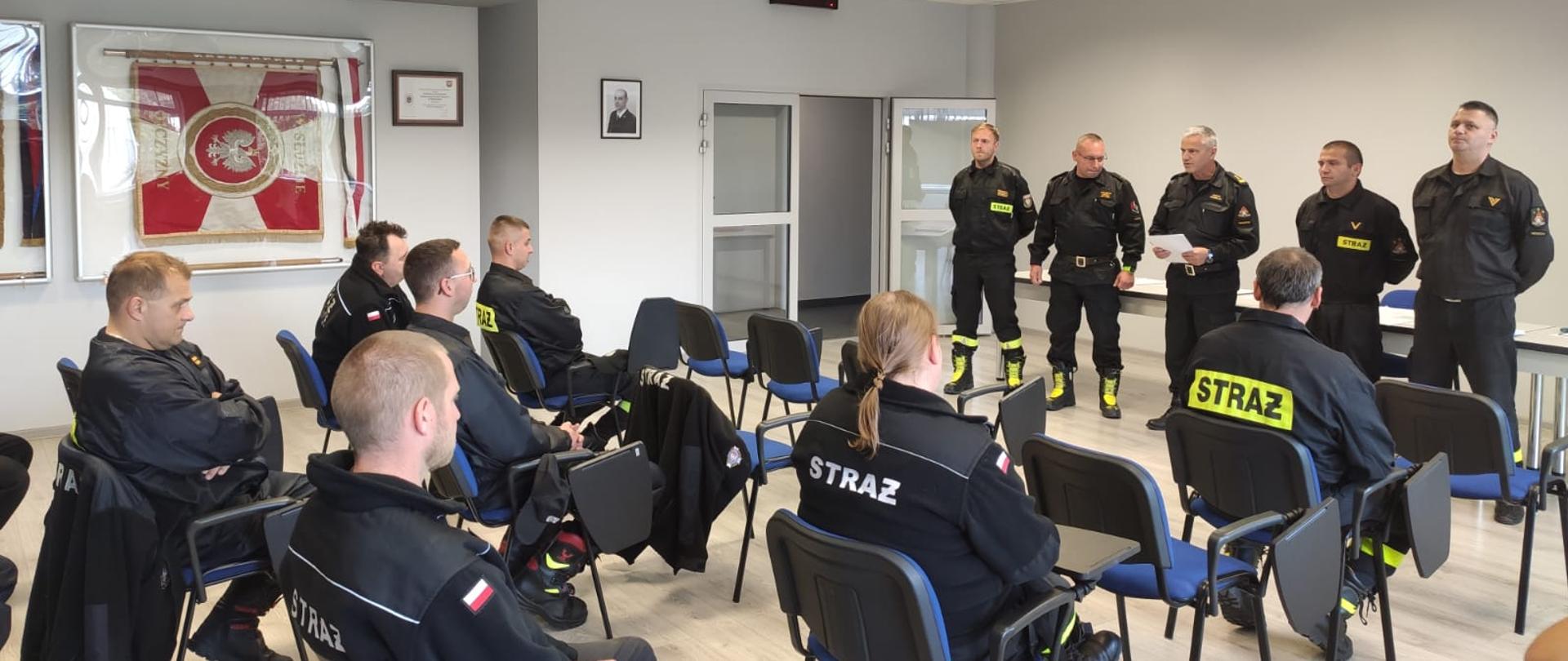 Zdjęcie przedstawia druhów czekających na wręczenie zaświadczeń zaliczenia egzaminu. Na drugim planie znajduje się komisja egzaminacyjna oraz osoby funkcyjne.