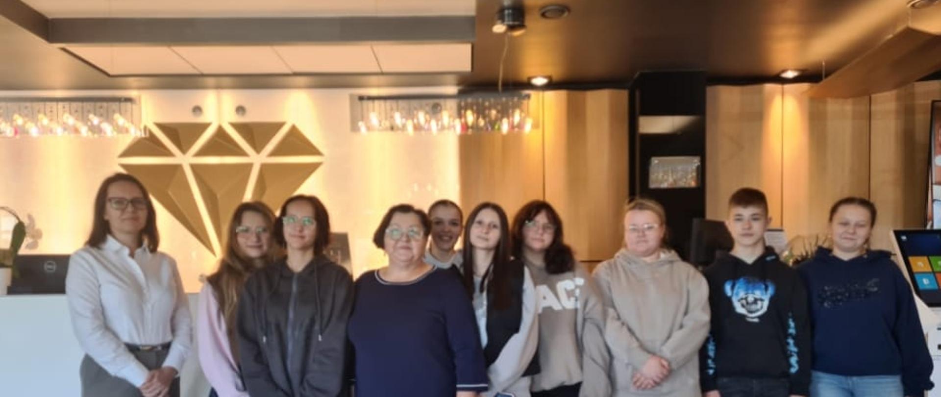 Uczniowie technikum z opiekunem i panią manager w hotelowej recepcji
