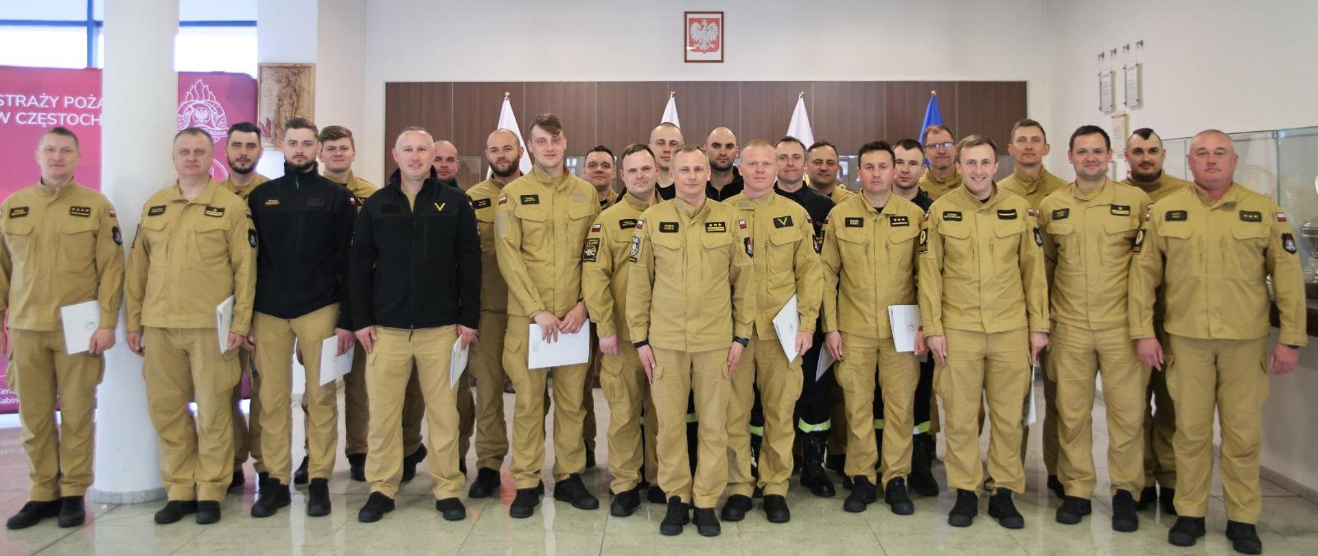 Pamiątkowe zdjęcie grupowe funkcjonariuszy (19 osób) będących uczestnikami warsztatów w towarzystwie Zastępcy Komendanta Centralnej Szkoły PSP oraz pięciu funkcjonariuszy CS PSP