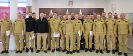 Pamiątkowe zdjęcie grupowe funkcjonariuszy (19 osób) będących uczestnikami warsztatów w towarzystwie Zastępcy Komendanta Centralnej Szkoły PSP oraz pięciu funkcjonariuszy CS PSP