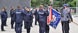 Czworo przedstawicieli nowych funkcjonariuszy ślubuje na sztandar. Poczet sztandarowy opuścił flagę do ślubowania