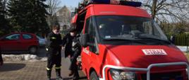 Strażak pomaga wysiąść z pojazdu pożarniczego starszemu mężczyźnie