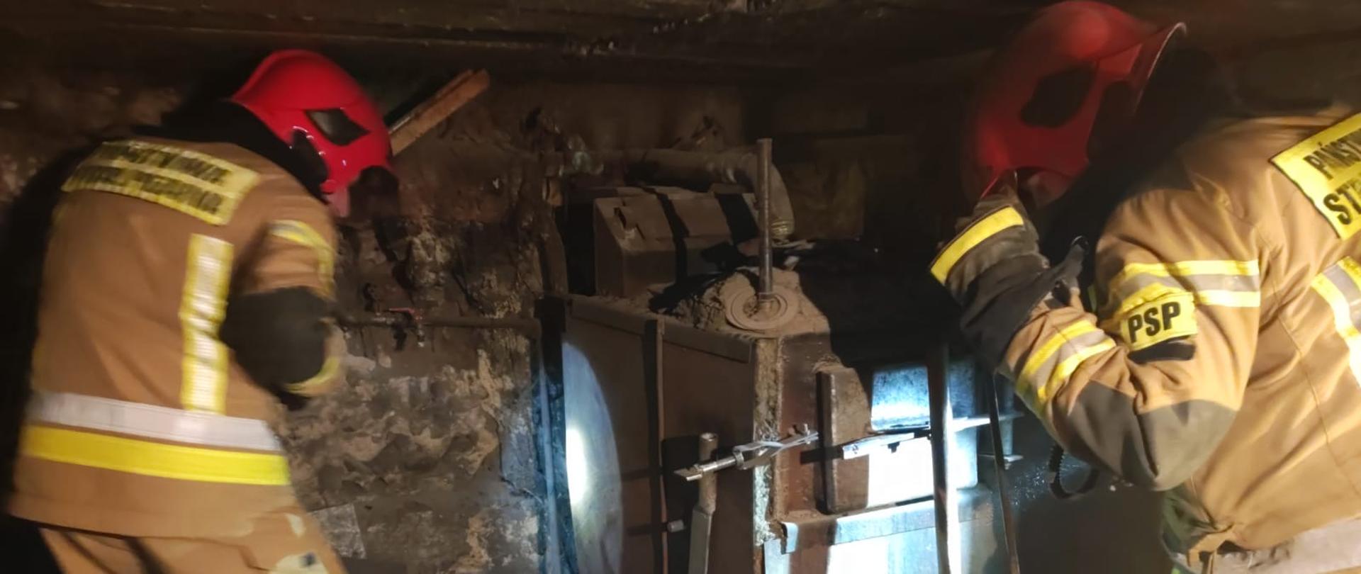 Na zdjęciu widać strażaków pracujących w pomieszczeniu kotłowni, które wcześniej zostało przewietrzone 