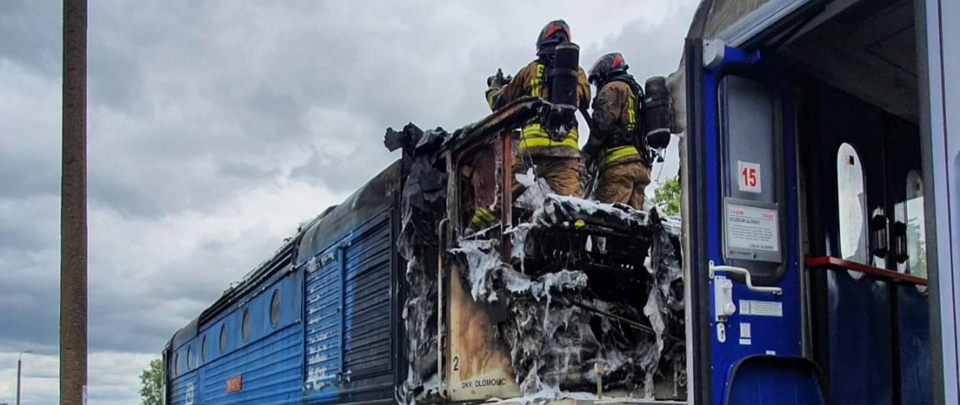 Widok na lokomotywę ze spaloną kabiną maszynistów, w której stoi dwóch strażaków