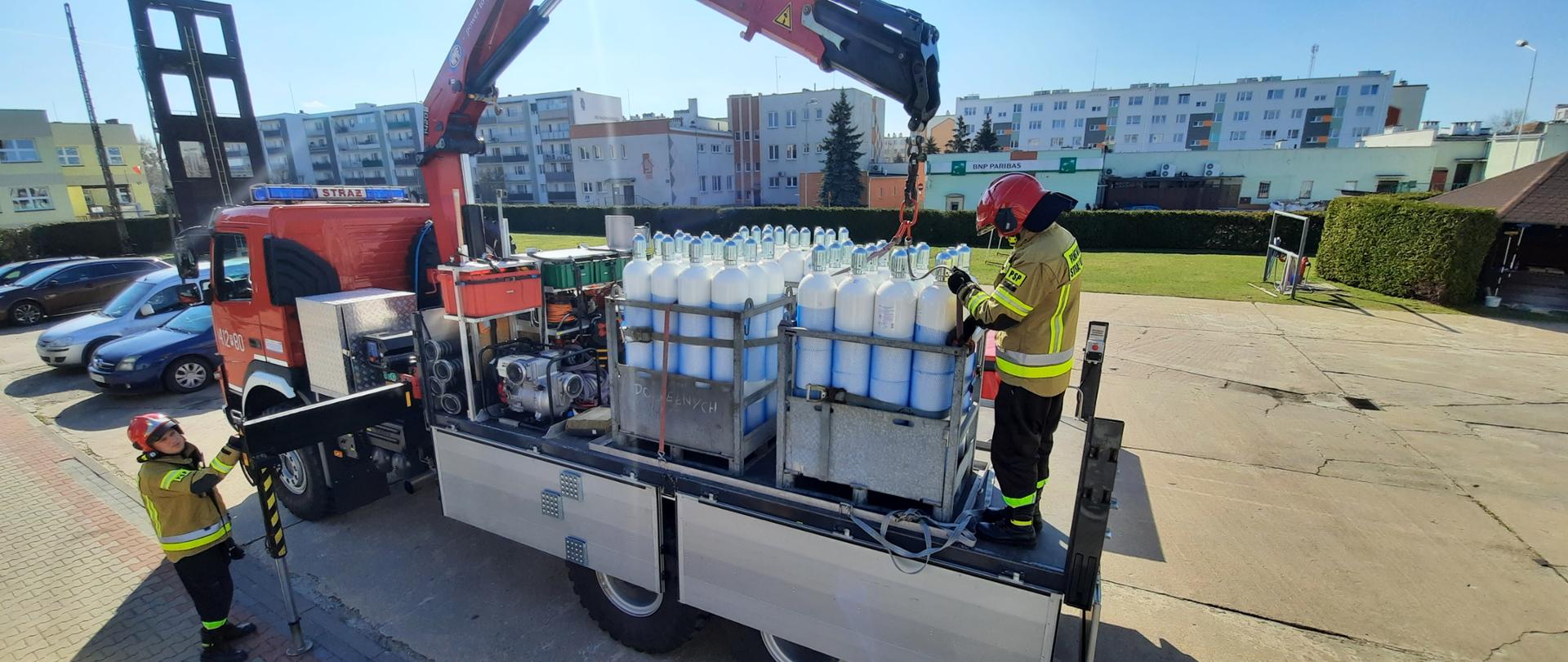 Załadunek butli z tlenem na ciężki samochód państwowej straży pożarnej