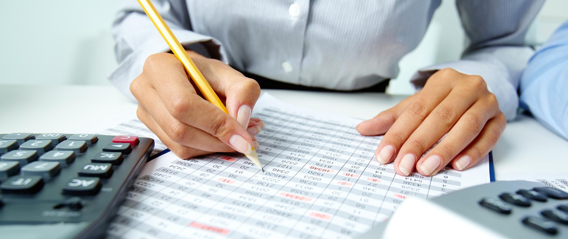 Photo of human hands holding pencil and ticking data in documents 
