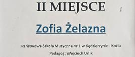 Na plakacie w jasnej, białej kolorystyce widoczny jest dyplom z niebieskimi i czarnymi elementami graficznymi, w tym logo z kluczem wiolinowym i postacią dziecka oraz ozdobnym motywem fal na dole.
Centralnie dużą czcionką zapisano „II MIEJSCE”, poniżej imię i nazwisko „Zofia Żelazna”, a wyżej informację o VI Ogólnopolskim Konkursie „Co Młodym w Duszy Gra?” wraz z datą 23–25 kwietnia 2026 roku i miejscem wydarzenia.
W dolnej części znajdują się nazwa szkoły, nazwisko pedagoga, podpisy jury i dyrektora oraz rząd logotypów patronów i sponsorów.
