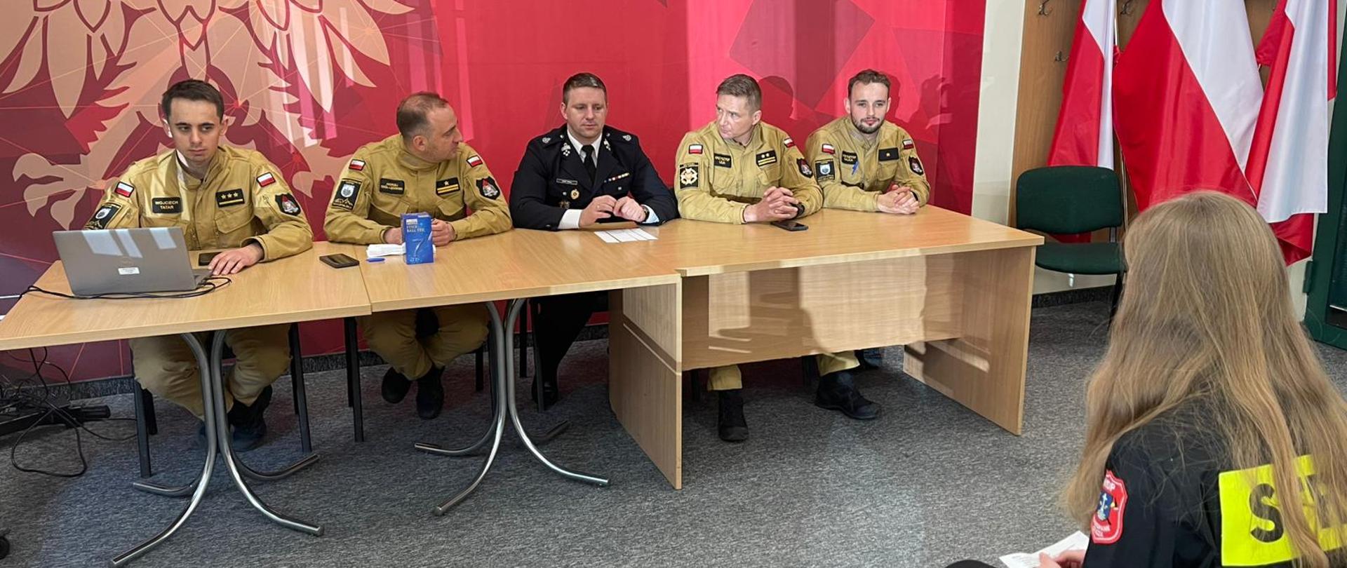 Zdjęcie przedstawia uczestników eliminacji turnieju pożarniczego i egzaminujących ich strażaków 