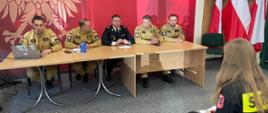 Zdjęcie przedstawia uczestników eliminacji turnieju pożarniczego i egzaminujących ich strażaków 