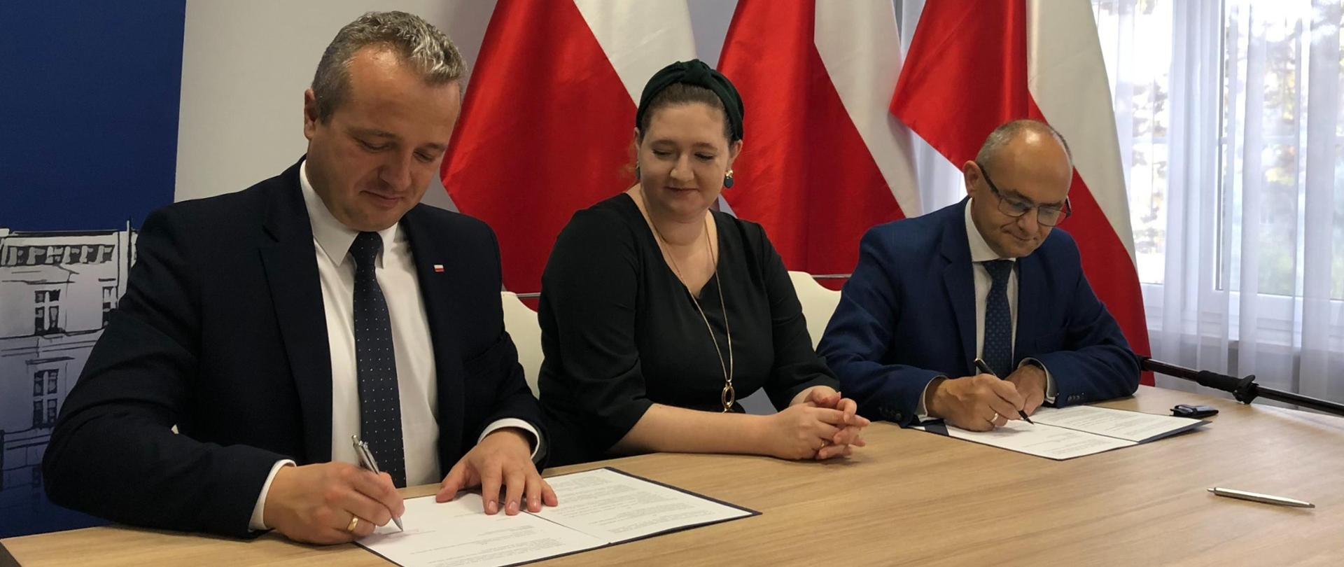 Kobieta i dwóch mężczyzn podczas podpisywania umowy