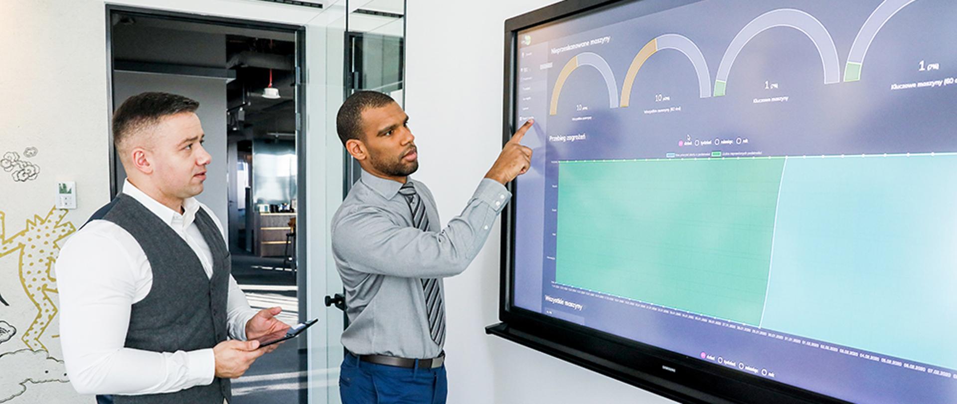 Dwóch mężczyzn podczas prezentacji na dużym monitorze