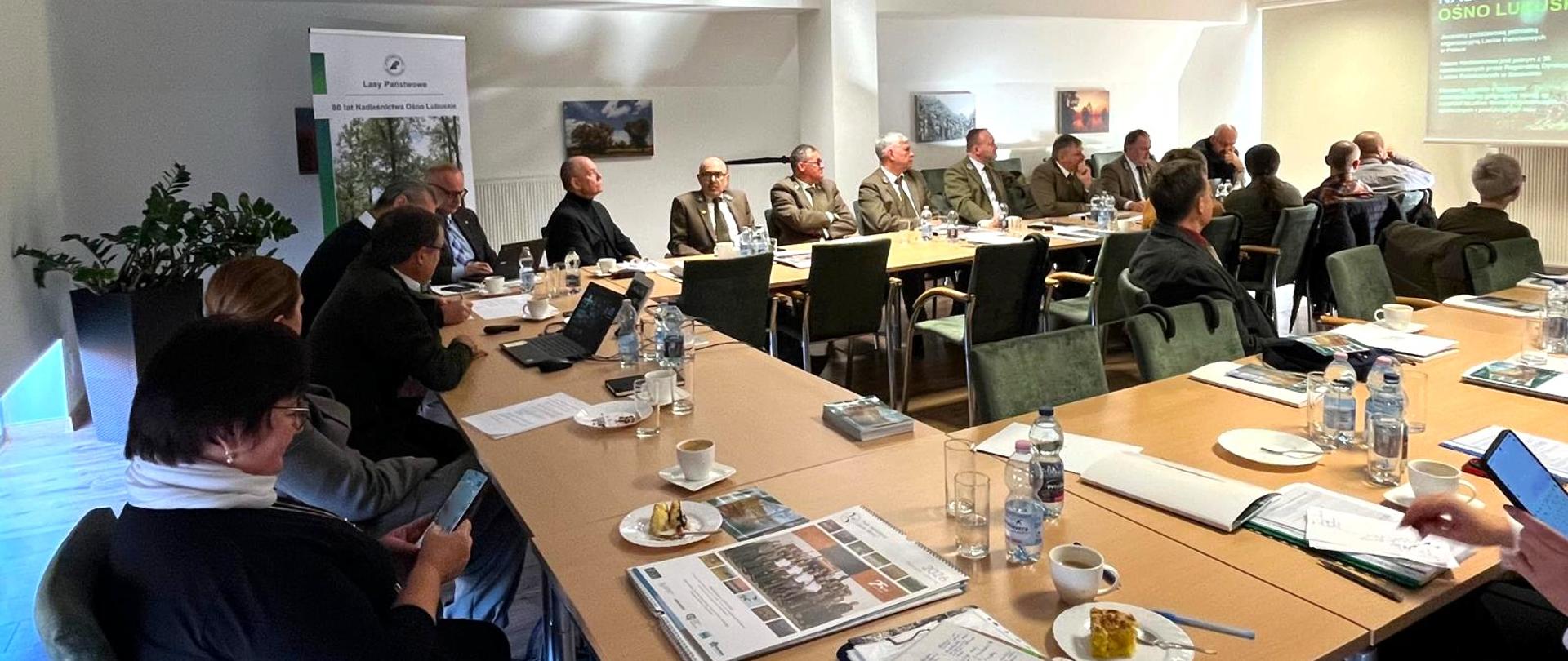 W sali konferencyjnej za stołami siedzi kilkadziesiąt osób. Przed nimi na na ekranie wyświetlana jest prezentacja.