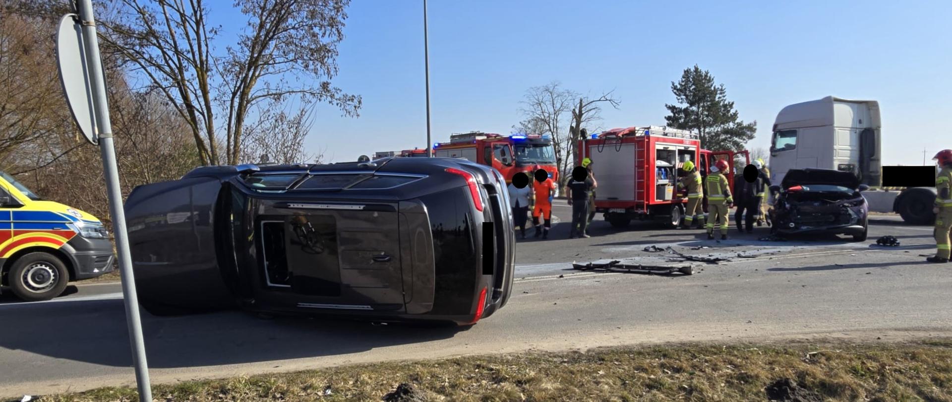 Samochód na lewym boku na drodze, po prawej drugi uszkodzony samochód