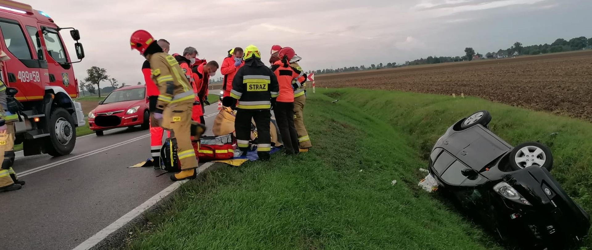 Fotografia przedstawia działania strażaków oraz ratowników medycznych podczas wypadku drogowego