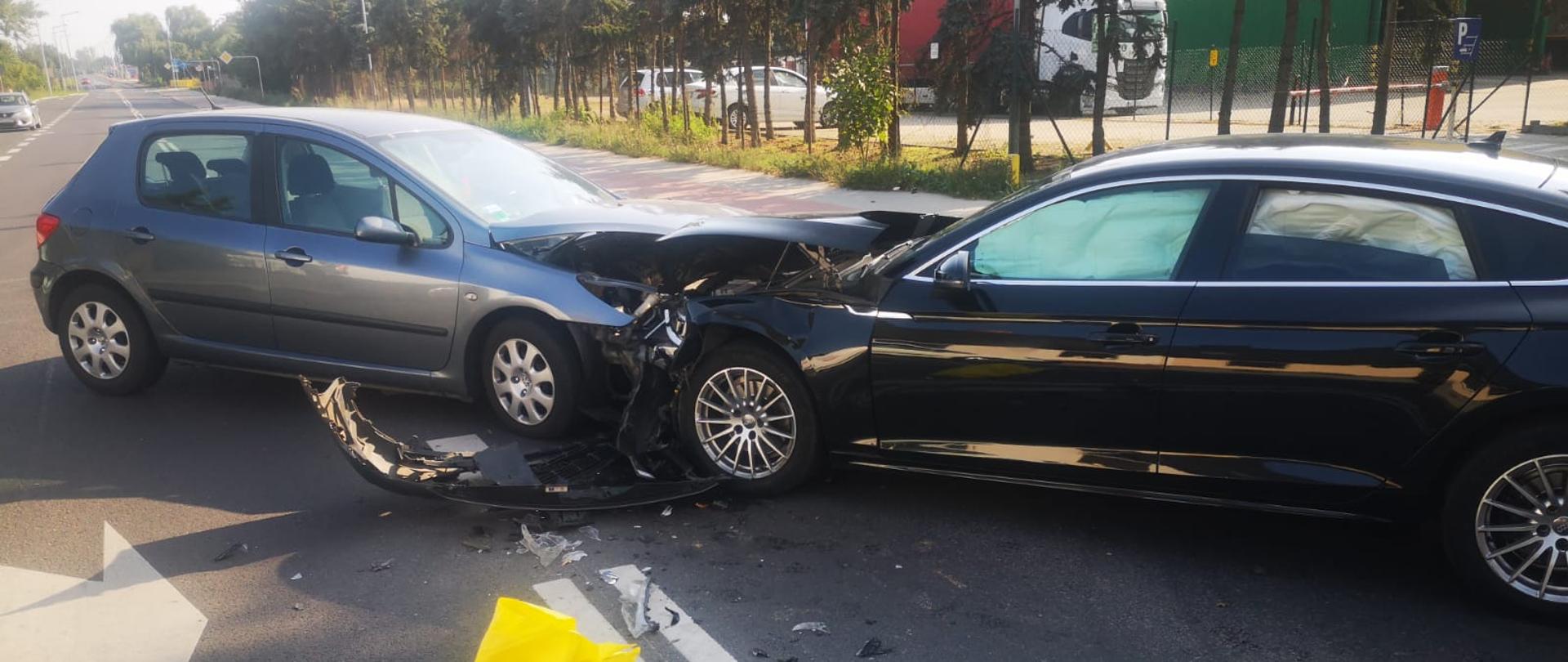 Widać dwa samochody na środku drogi, oba mają uszkodzony przód