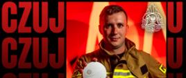 Strażak w ręce trzyma czujkę dymu a w drugiej hełm