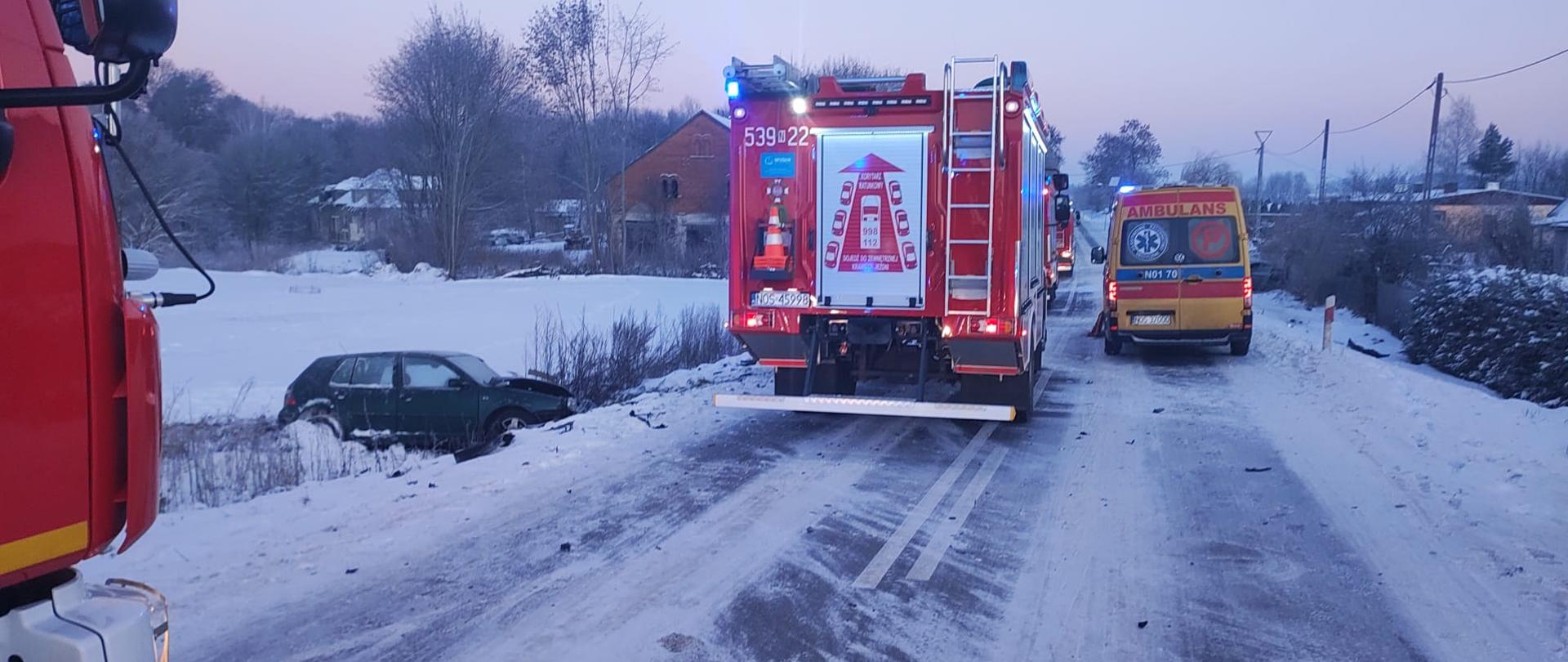Pojazdy straży pożarnej i zespołu ratownictwa medycznego stoją na jezdni w miejscu zdarzenia