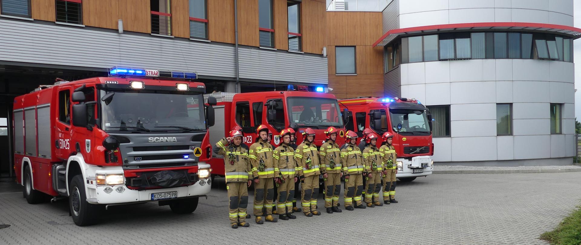 Strażacy na tle samochodów pożarniczych
